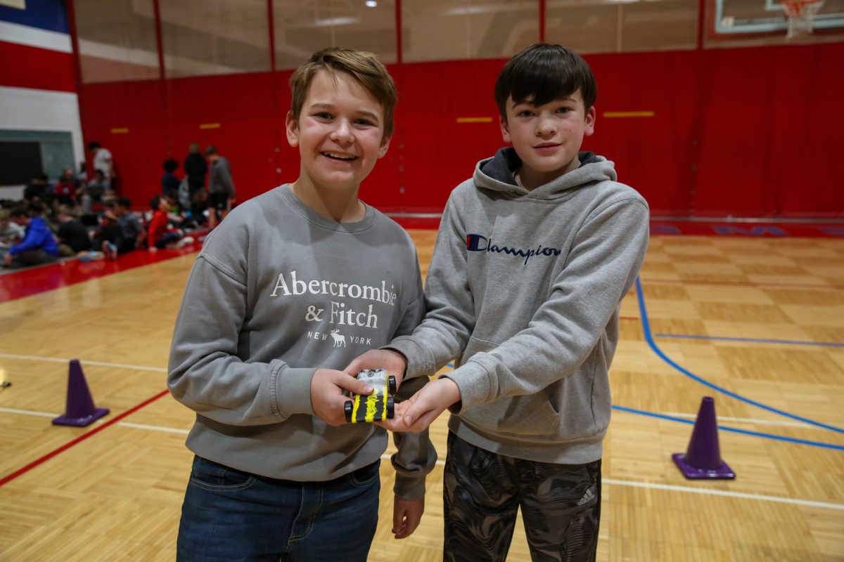 students hold pinewood derby car