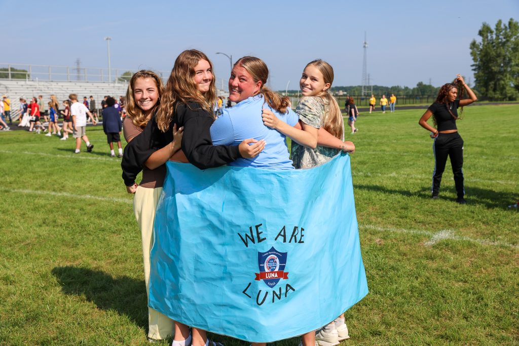 A teacher and students holding a "We are Luna" poster